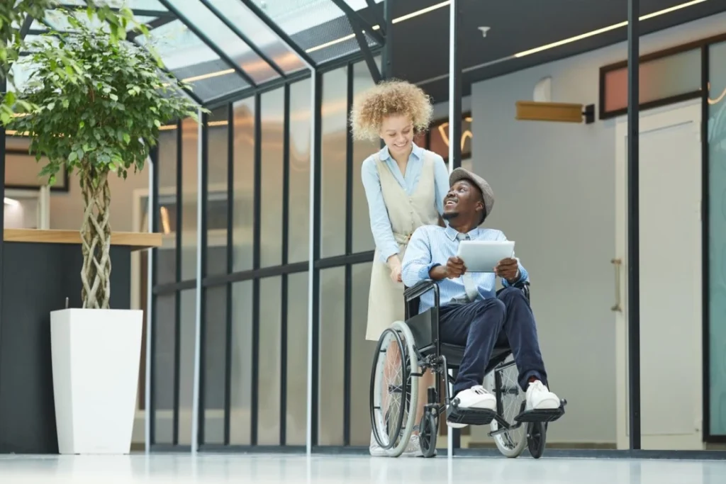 Man in wheelchair looking up and smiling at carer who is pushing wheelchair