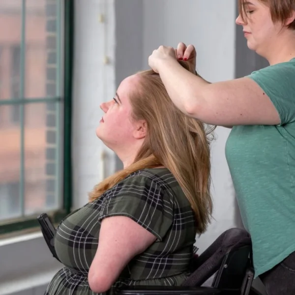 Disabled woman in wheelchair with carer doing her hair